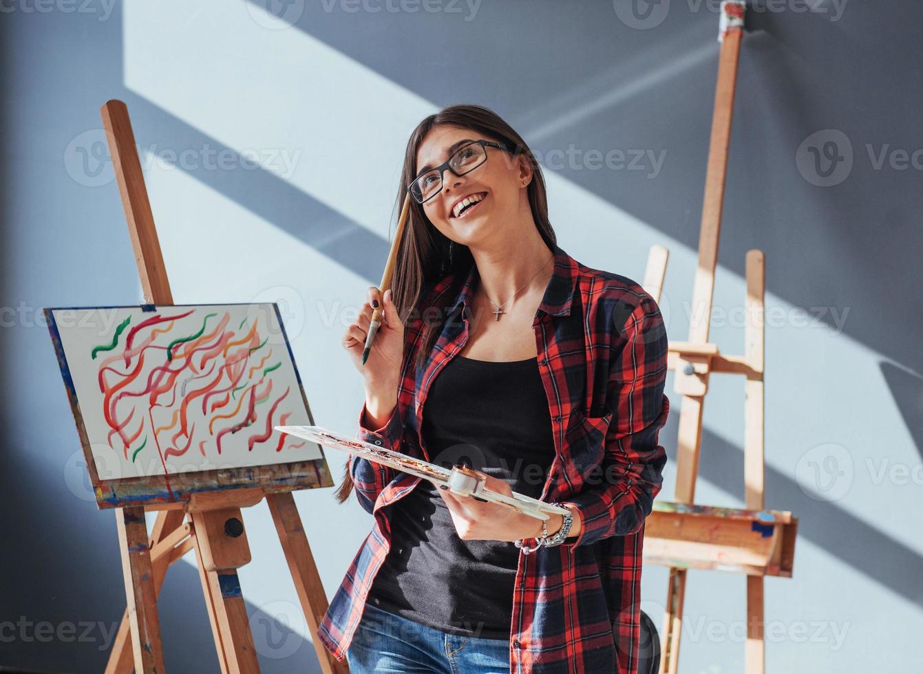 Dark-haired artist holding a brush in his hand and draws a picture on canvas. Thinks that draw on photo