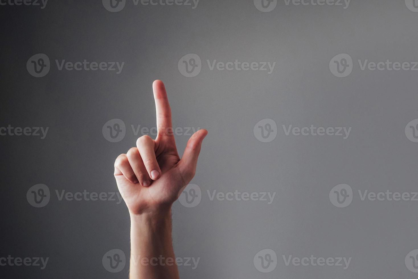Close up view of the human hand, touching his index finger on a gray background. Valet touchscreen. Pointing at something. Body Language. photo
