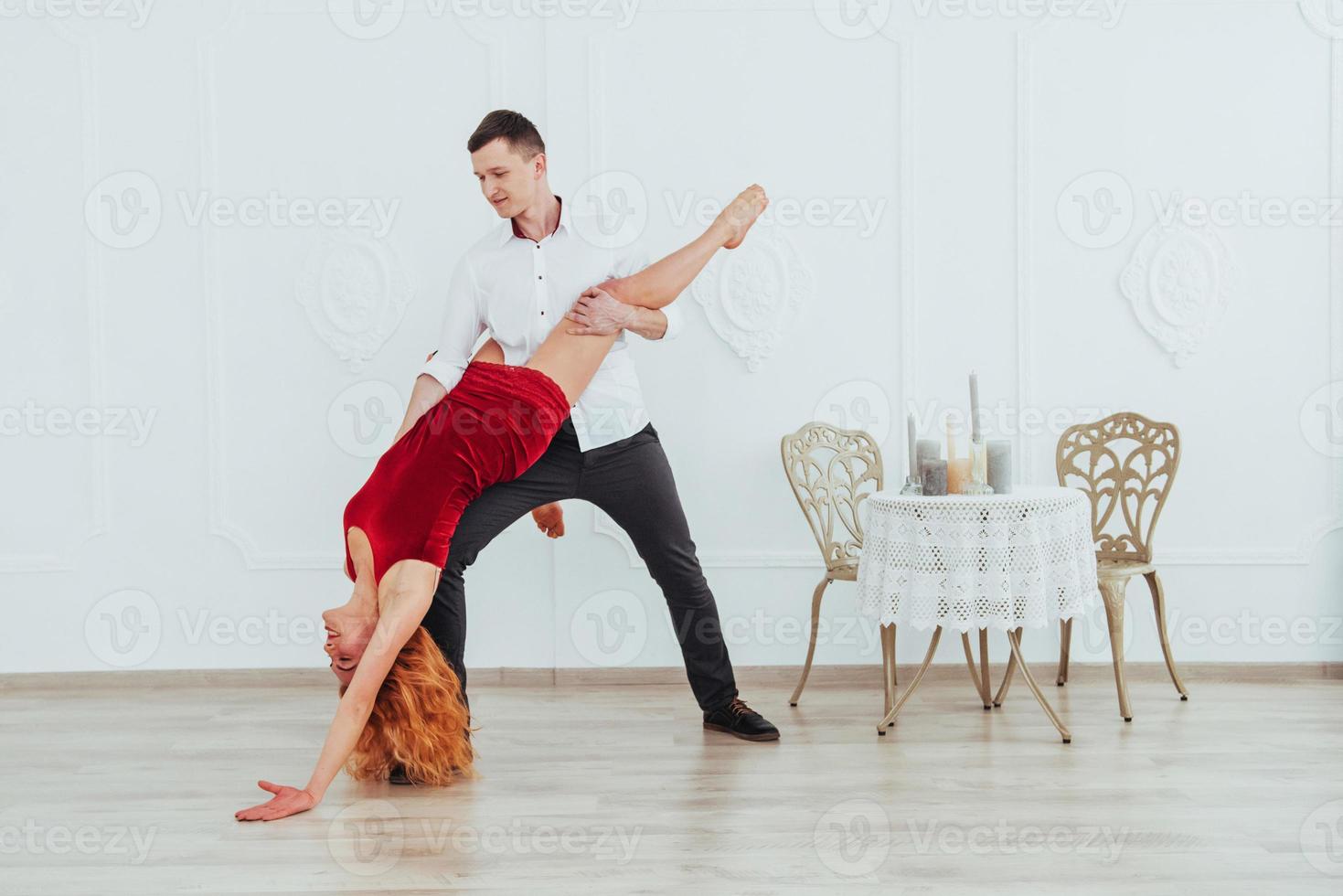 Young beautiful woman in a red dress and a man dancing, isolated on a white background. photo