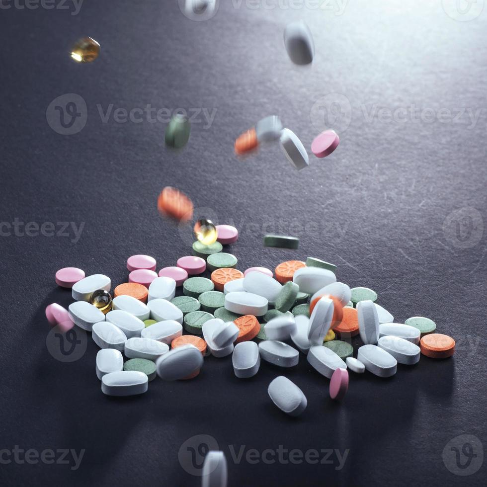 píldoras, cápsulas o suplementos coloridos médicos para el tratamiento y la atención de la salud en un fondo negro foto