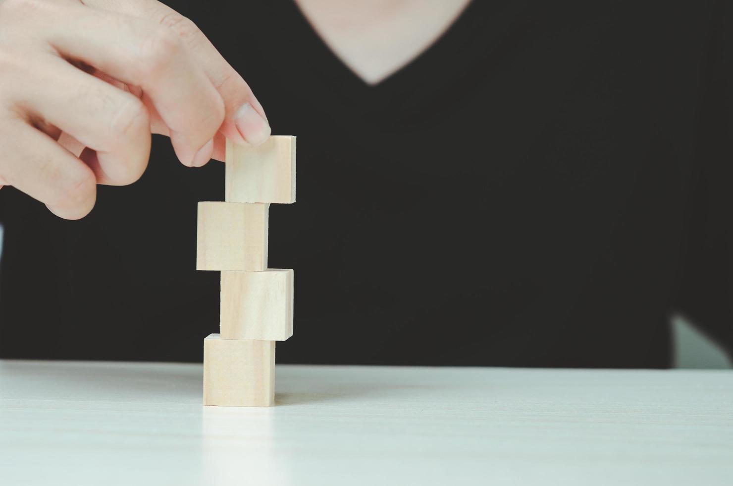 Hand putting and stacking blank wooden cubes  for icons or symbols. photo