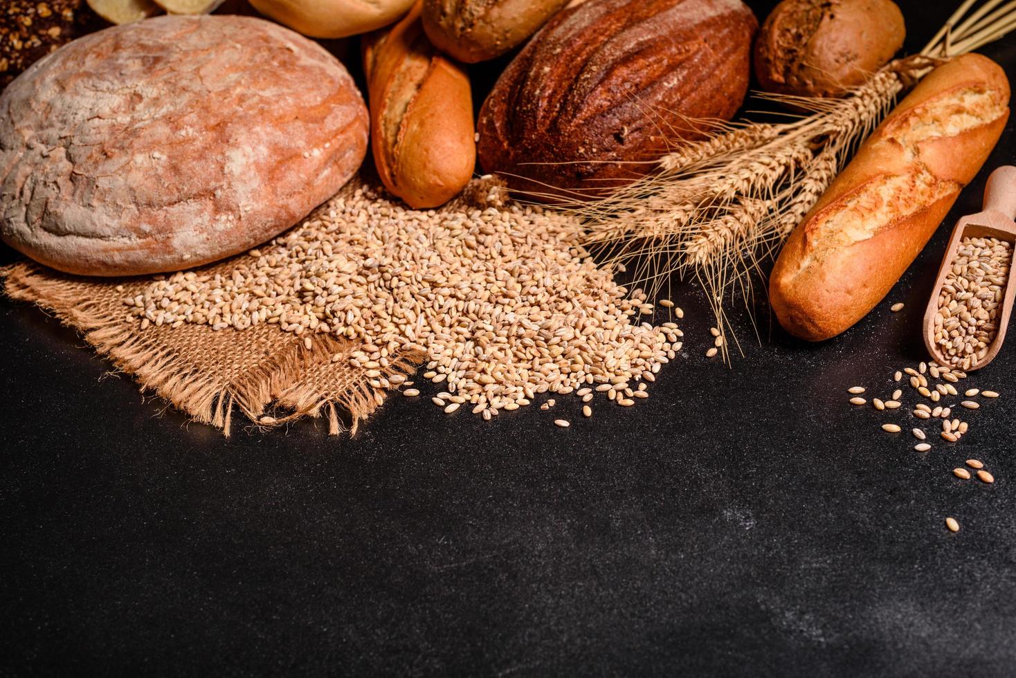 Beautiful fresh baked bread with wheat grains on a dark concrete background photo