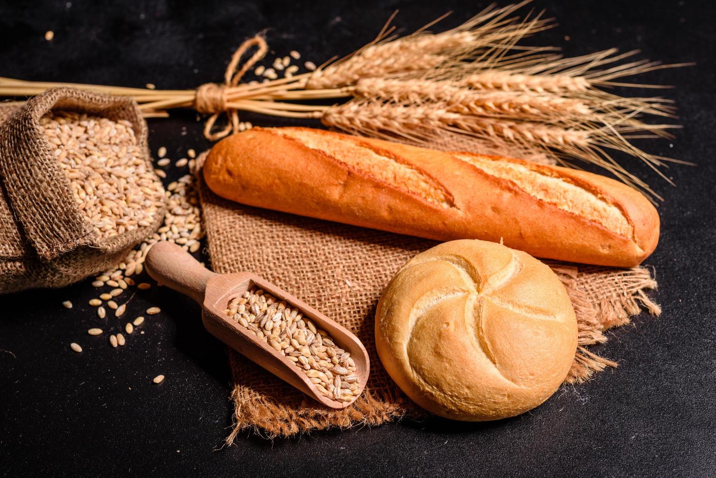 Beautiful fresh baked bread with wheat grains on a dark concrete background photo