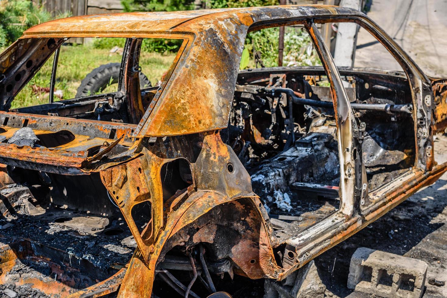 Burnt passenger car on the street of a dysfunctional area photo
