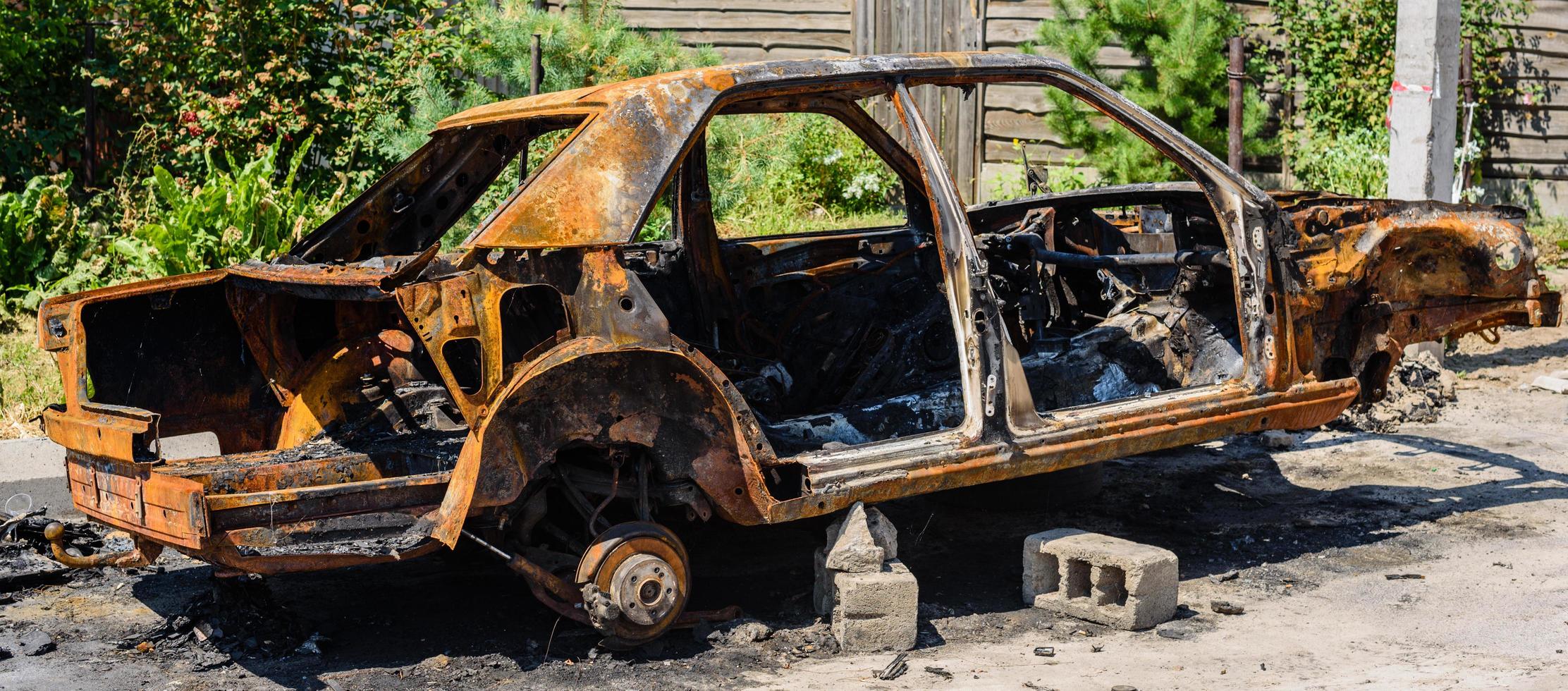 Burnt passenger car on the street of a dysfunctional area photo