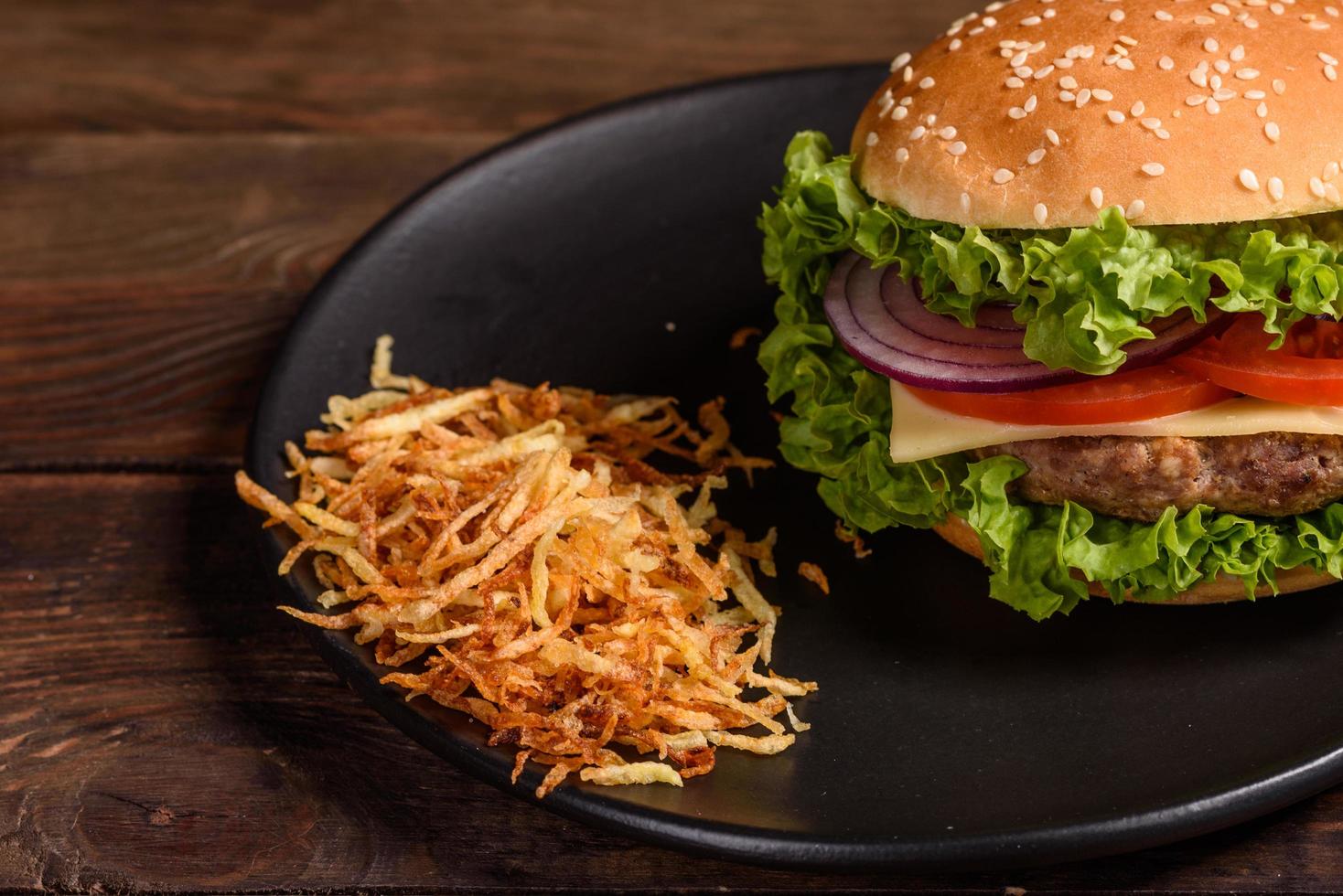 deliciosa hamburguesa fresca y jugosa con chuleta de ternera, queso, tomates y cebollas foto