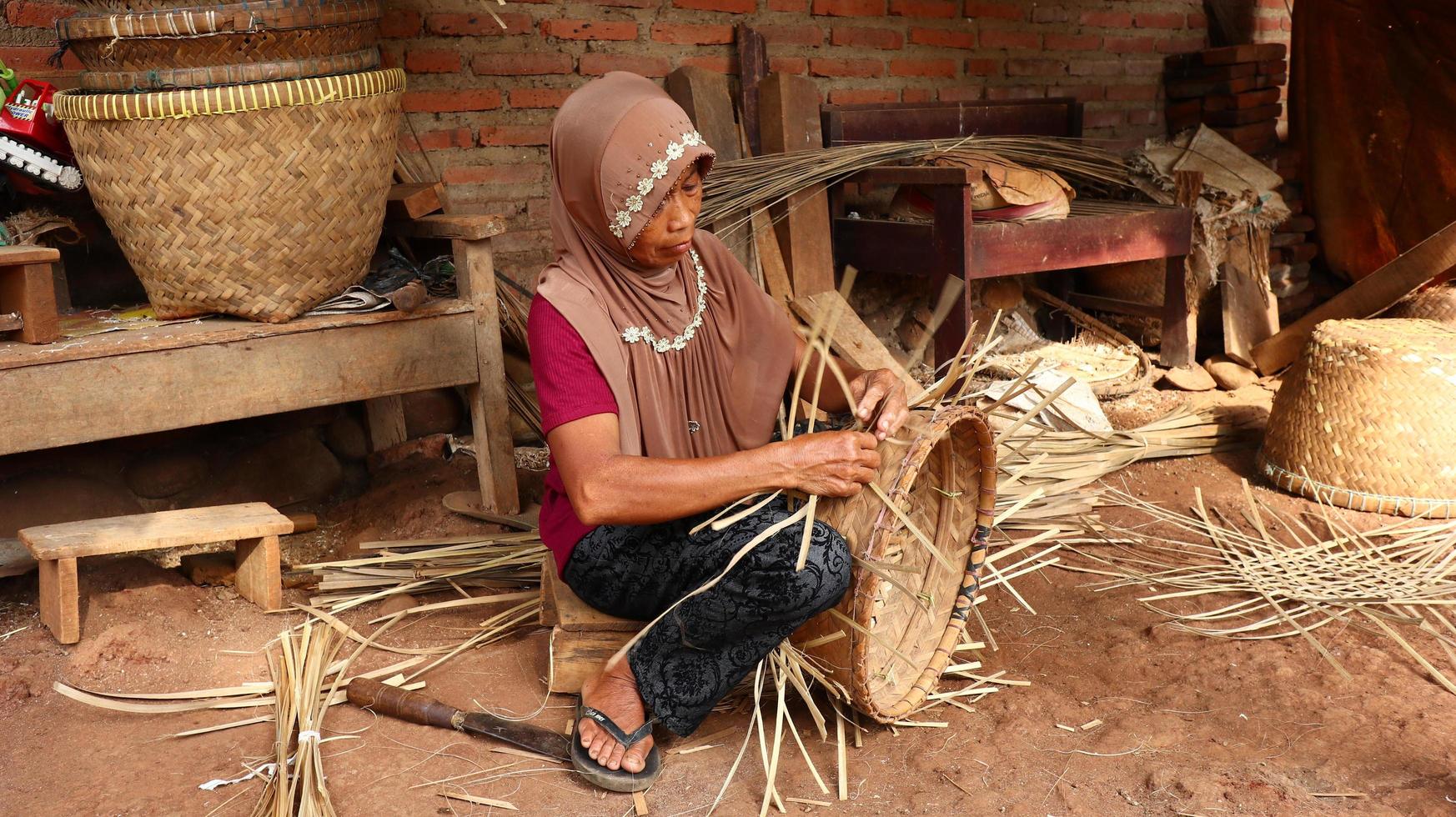 artesana de la cesta de bambú mientras hace su trabajo en un lugar, Batang, Jawa Tengah, Indonesia, 26 de mayo de 2019 foto