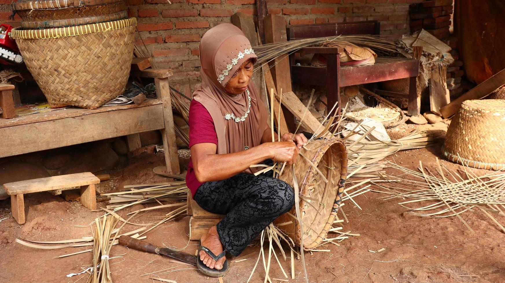 artesana de la cesta de bambú mientras hace su trabajo en un lugar, Batang, Jawa Tengah, Indonesia, 26 de mayo de 2019 foto