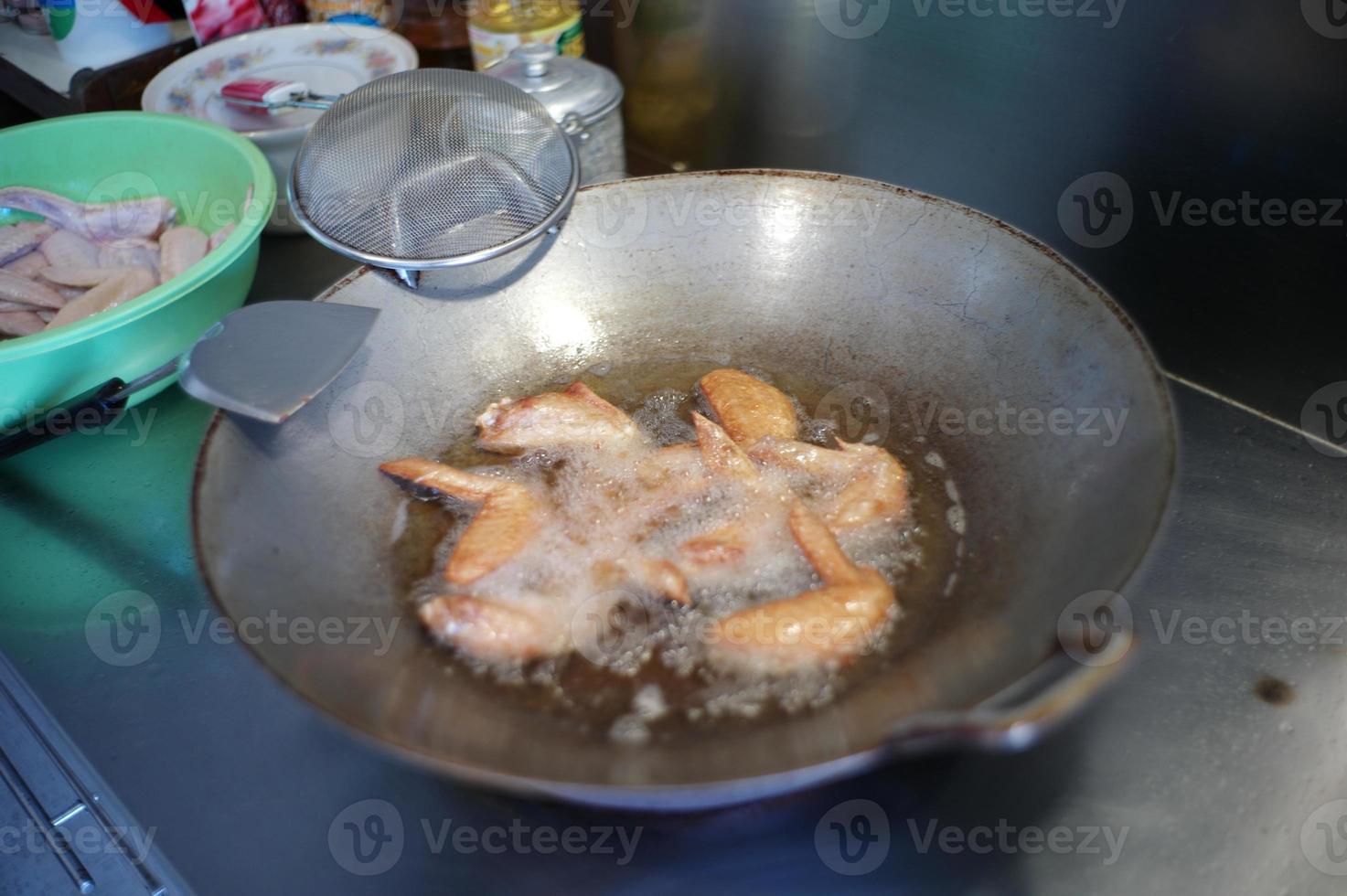 Selective focus on many pieces of chicken wings deep fried in the boiled vegetable oil. photo