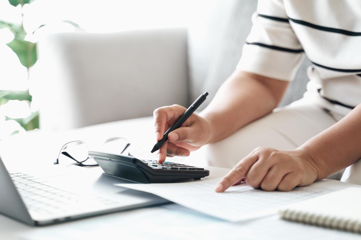 la mujer está calculando el impuesto anual con calculadora y llenando el formulario de declaración de impuestos sobre la renta individual. temporada para pagar impuestos y concepto de planificación presupuestaria. foto