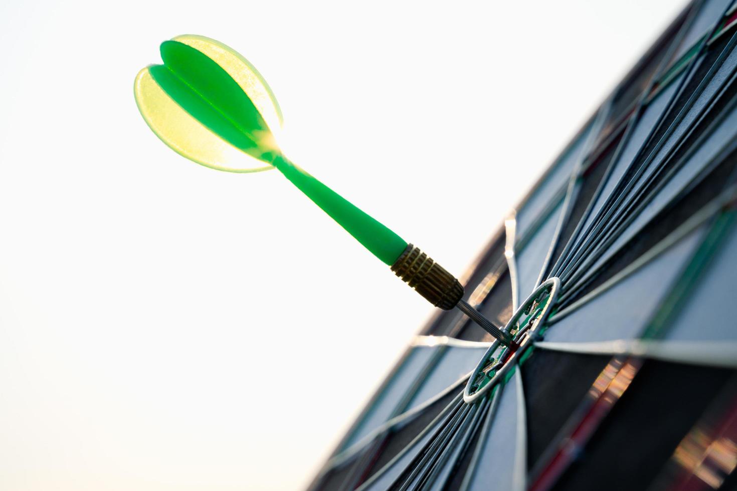 Close up shot green darts arrows in the target center on sky background. Business target or goal success and winner concept. photo