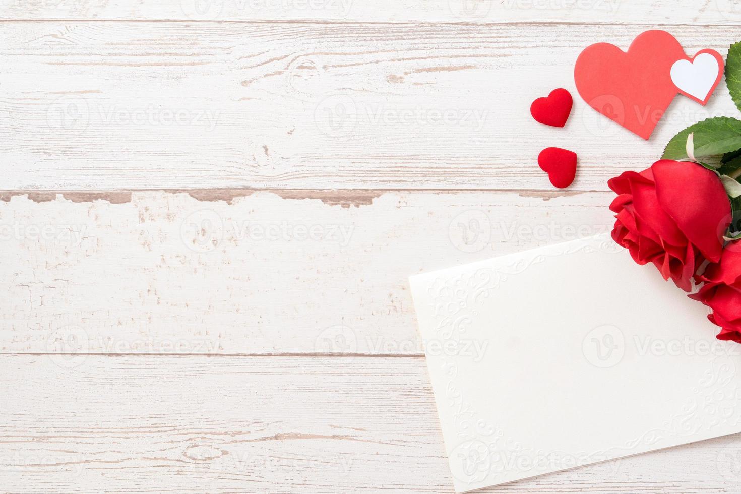 Greeting concept - Beautiful roses and hearts shape with white empty card isolated on a bright wooden table, copy space, flat lay, top view, mock up photo