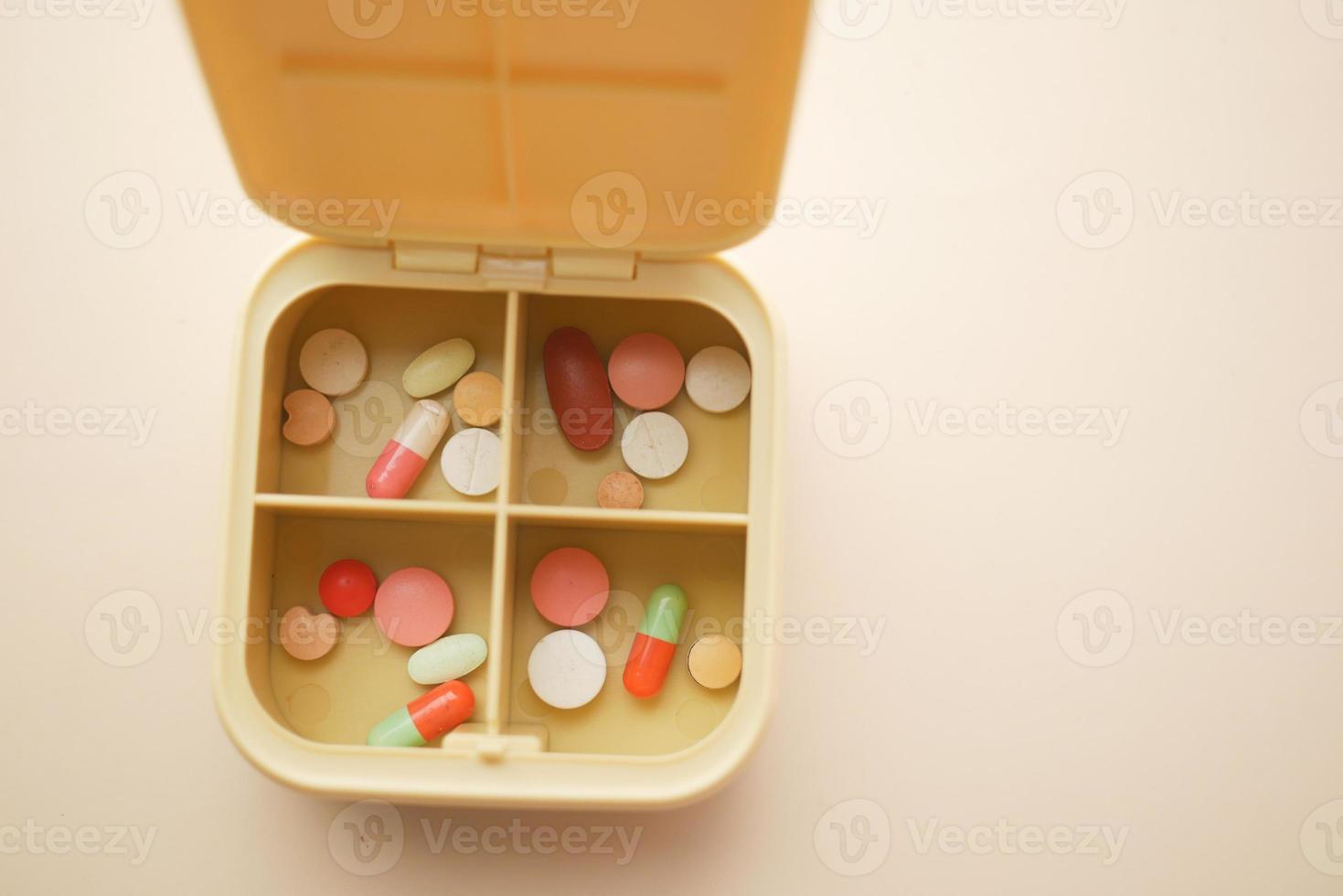 close up of medical pills in a pill box on color background photo