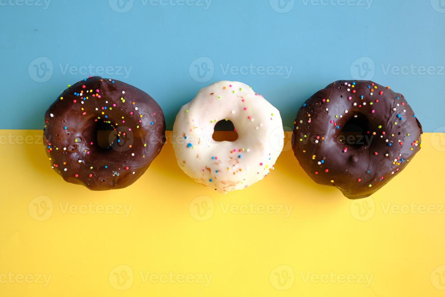 Close up of many chocolate donuts on color background photo