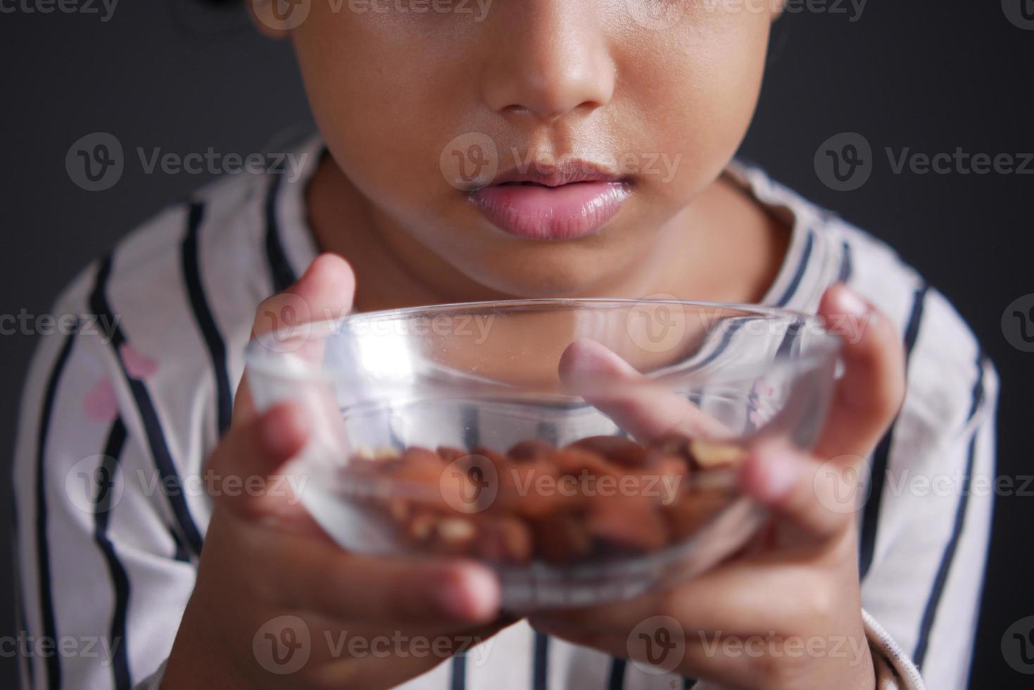 kid hand holding a bowl of almond on black photo