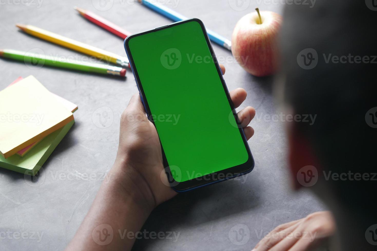 rear view of child hand pointing finger on smart phone screen. photo