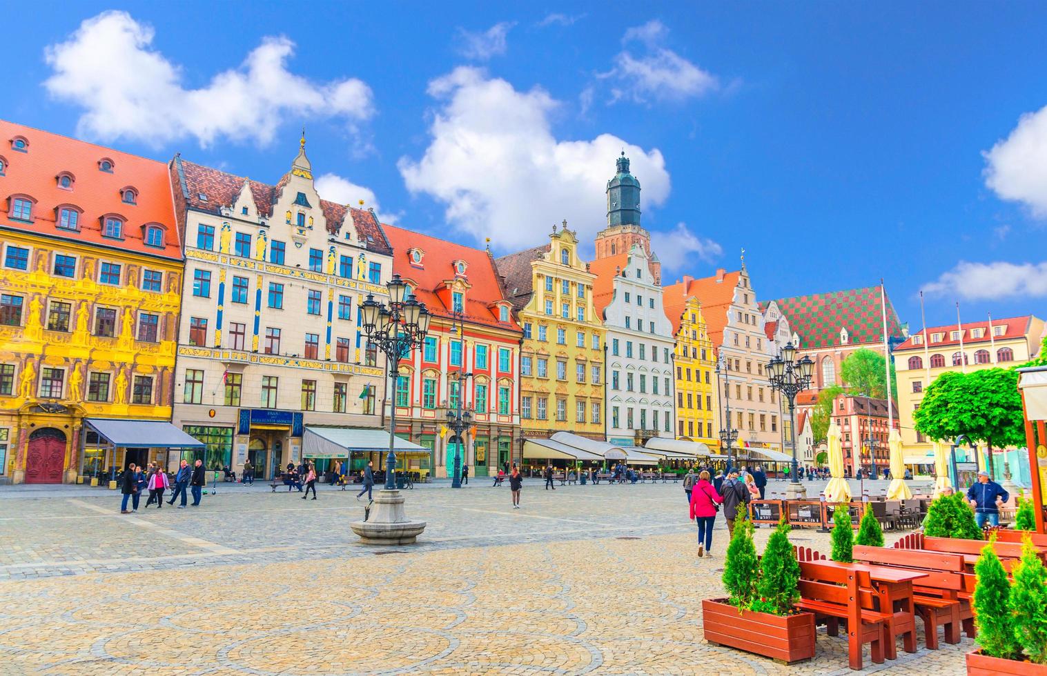 Wroclaw, Poland, May 7, 2019 Row of colorful traditional buildings with art facades, St. Elizabeth Basilica catholic Church and walking people on Rynek Market Square in old historical city centre photo