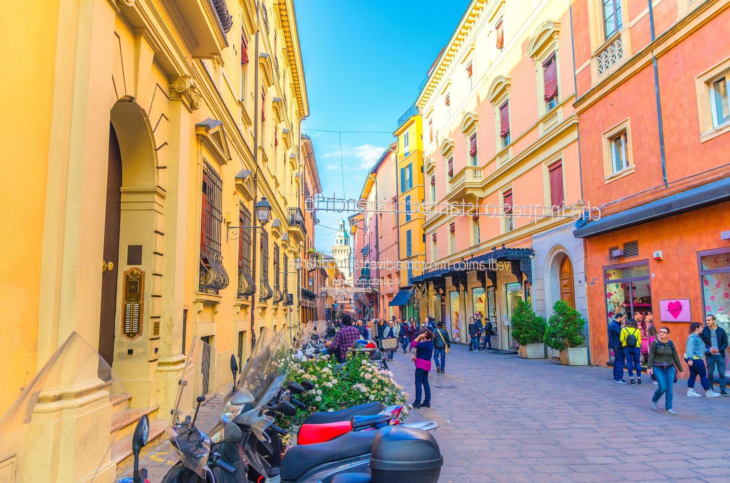 bolonia, italia, 17 de marzo de 2019 personas caminando por la calle peatonal vía massimo d'azeglio con palabras colgantes letras oraciones arriba entre edificios en el antiguo centro histórico de la ciudad, emilia-romagna foto