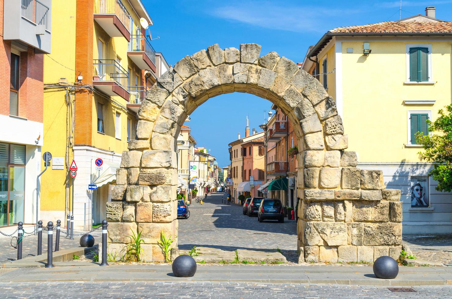 rimini, italia, 19 de septiembre de 2018 ruinas del antiguo arco de piedra puerta montanara entre edificios típicos italianos tradicionales en la calle en el antiguo centro histórico de la ciudad turística, emilia-romagna foto