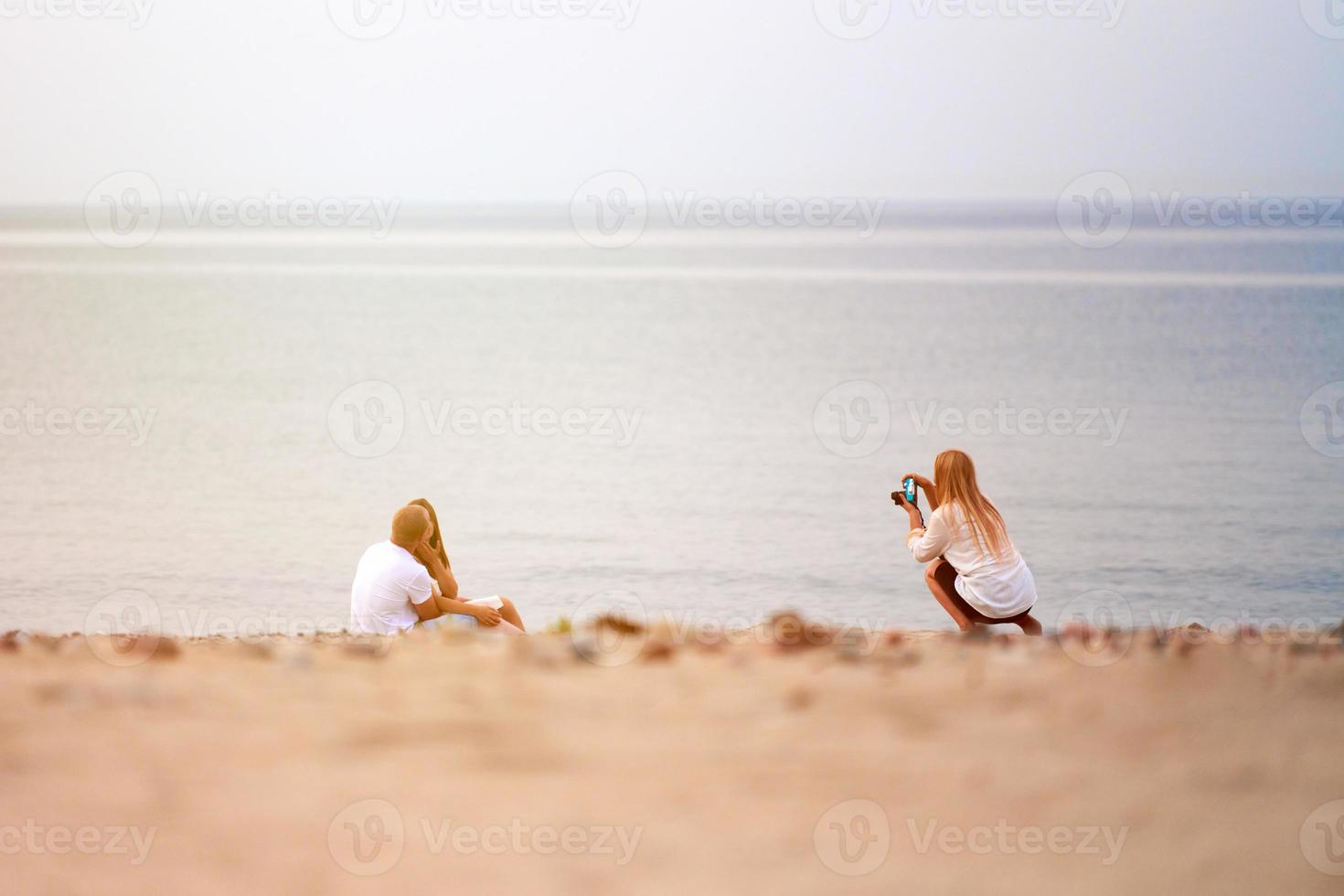 Photographer shooting loving couple in love on sandy beach, seascape horizon background outdoor photo