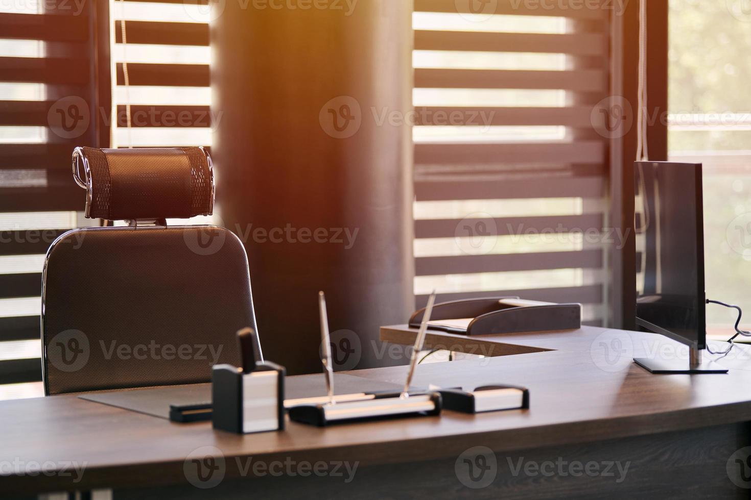 lugar de trabajo de la oficina de negocios. luz solar en el lugar de trabajo para jefe, jefe u otros empleados. mesa y silla cómoda. luz a través de las persianas entreabiertas foto