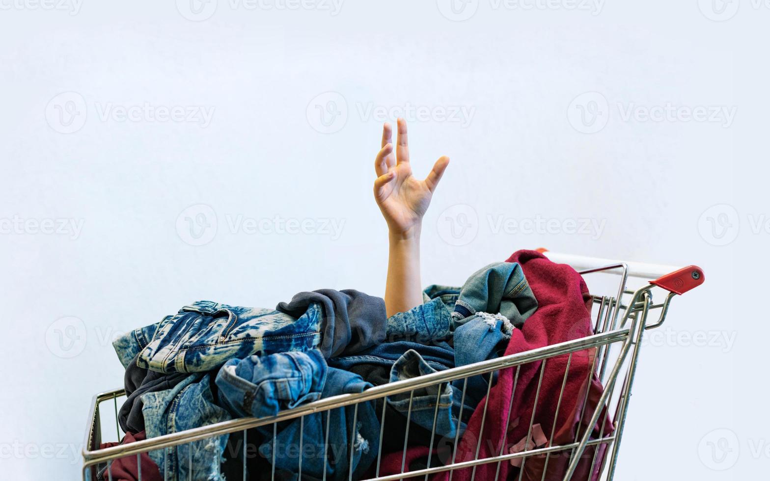 Shopaholic concept. Female hand sticks out of shopping cart photo