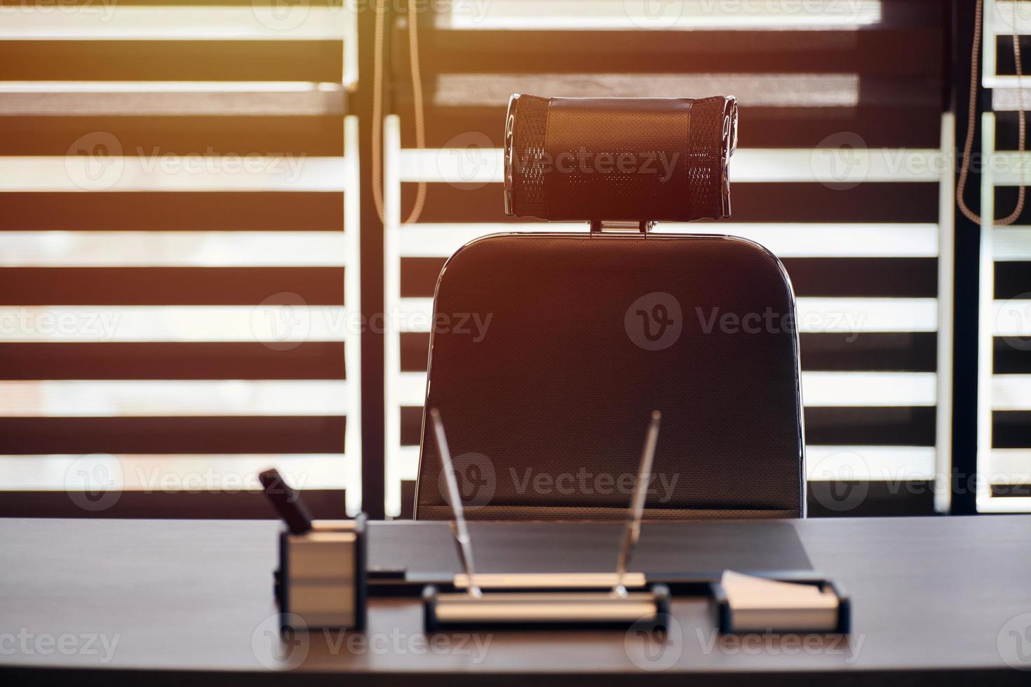 lugar de trabajo de la oficina de negocios. luz solar en el lugar de trabajo para jefe, jefe u otros empleados. mesa y silla cómoda. luz a través de las persianas entreabiertas foto