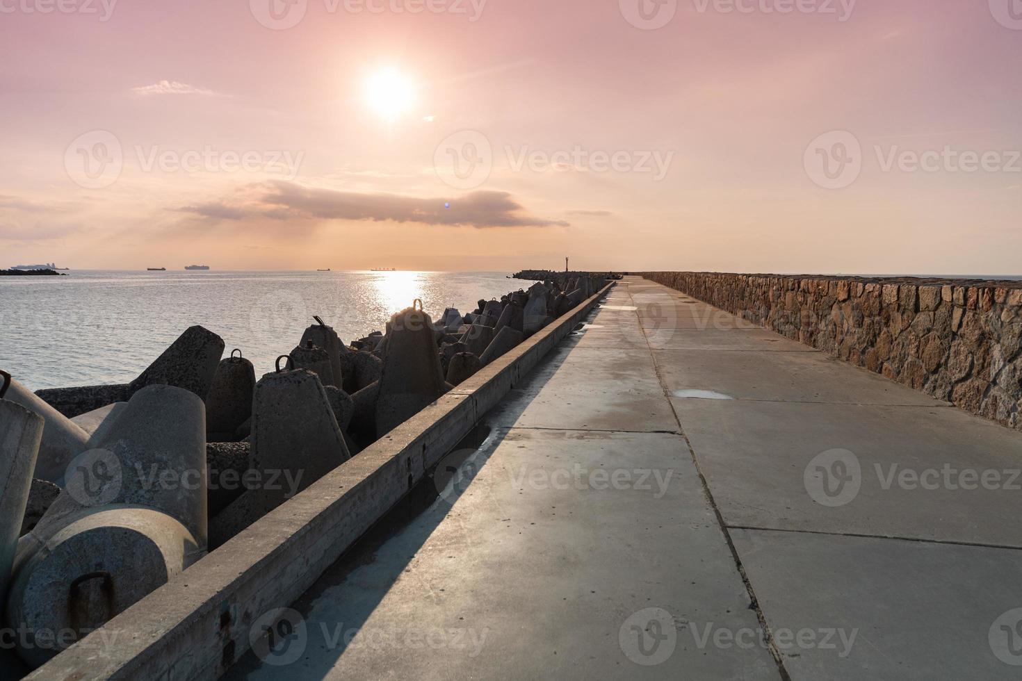 muelle norte con rompeolas, paisaje marino al atardecer, tetrápodos a lo largo de los bordes del muelle, hermoso paisaje marino nocturno, faro moderno a la luz del sol. foto