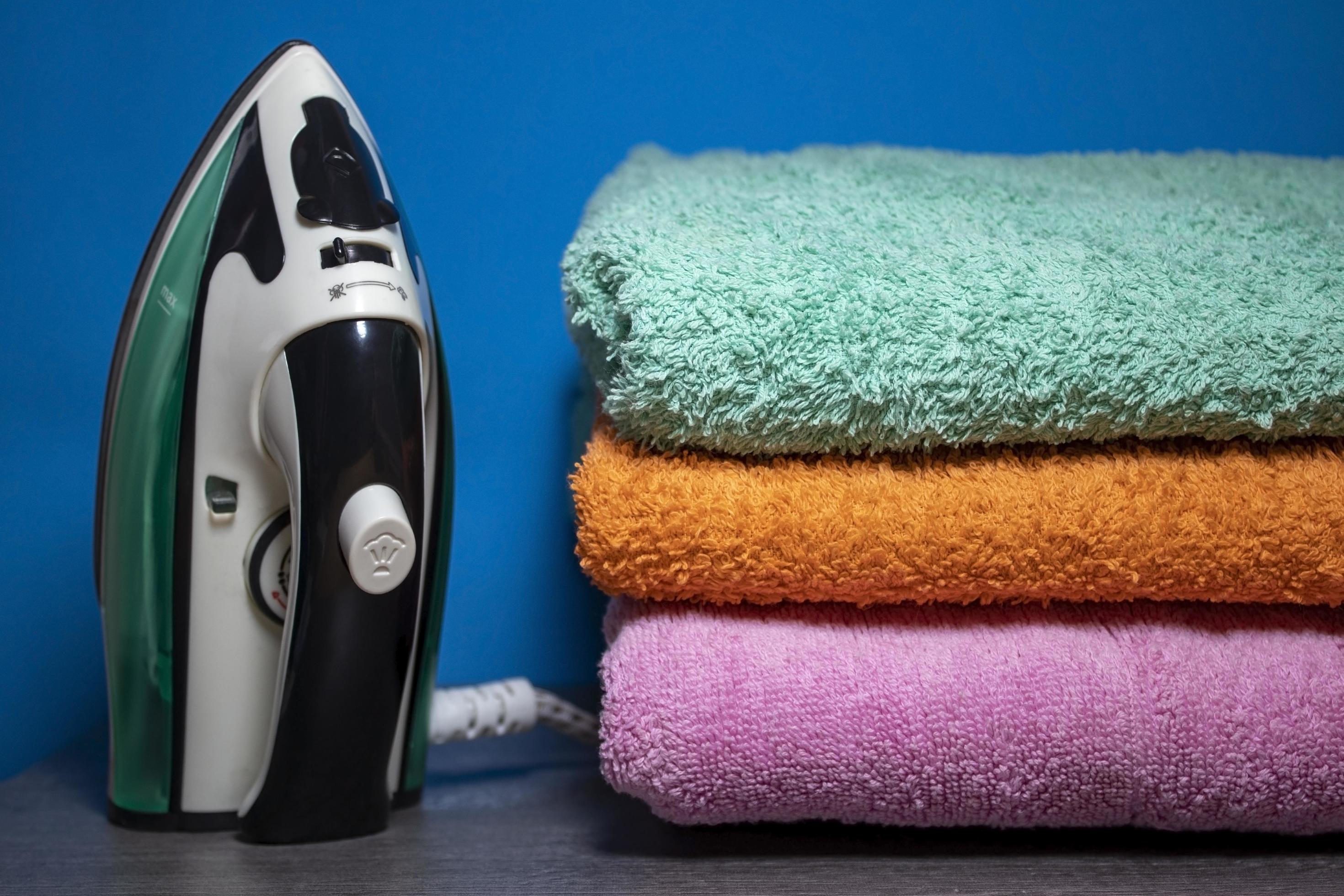 New Iron and Ironing Towels on the Table. Iron Irons linen. Pile of