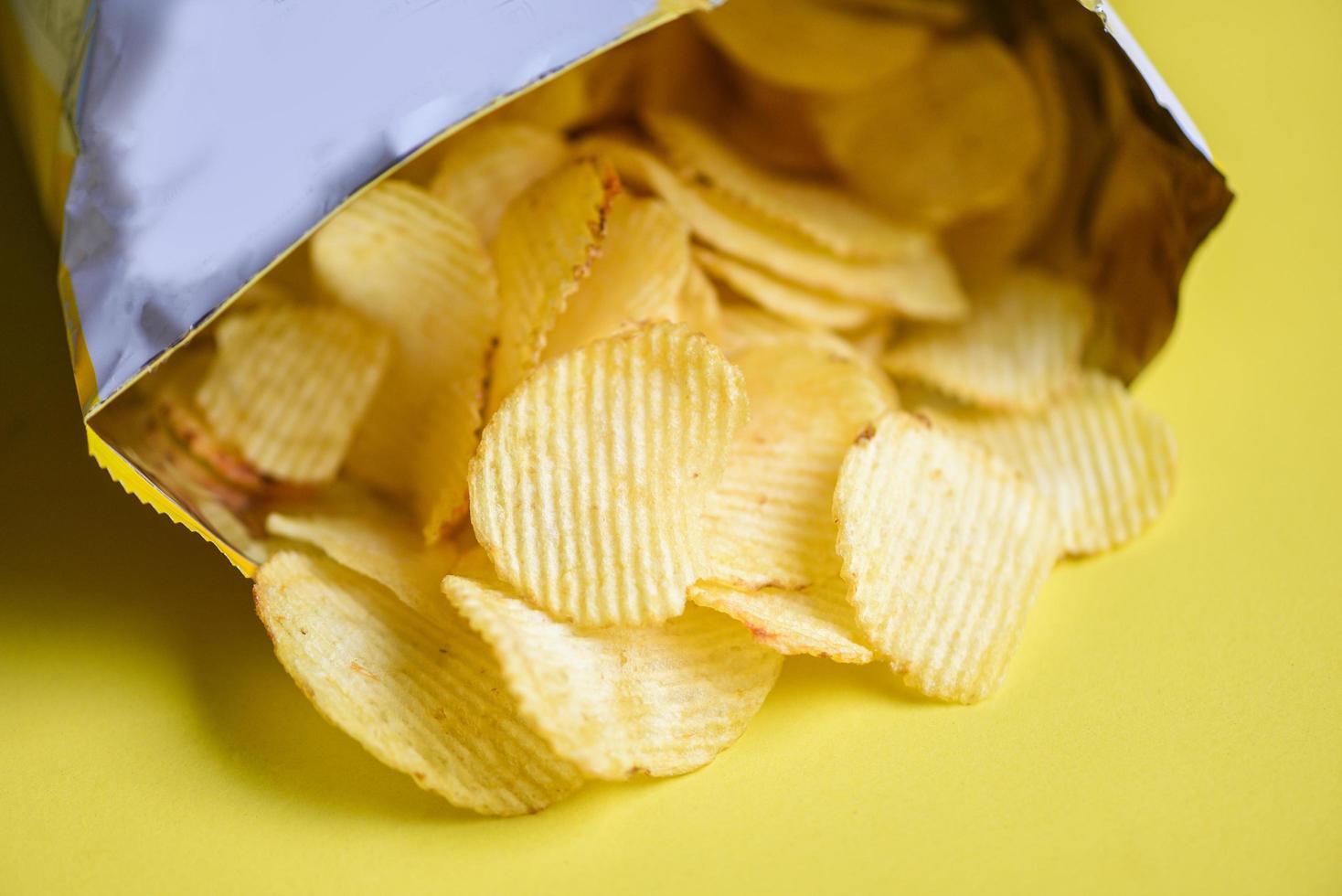 Potato hips on yellow background, Potato chips is snack in bag package wrapped in plastic ready to eat and fat food or junk food photo