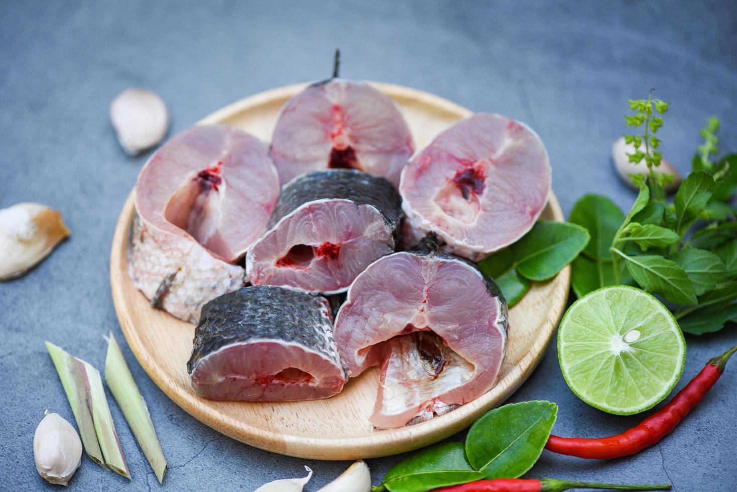 Snakehead fish for cooking food, striped snakehead fish chopped with ingredients lemon on wooden plate and table kitchen background, Fresh raw Snake head fish menu freshwater fish photo