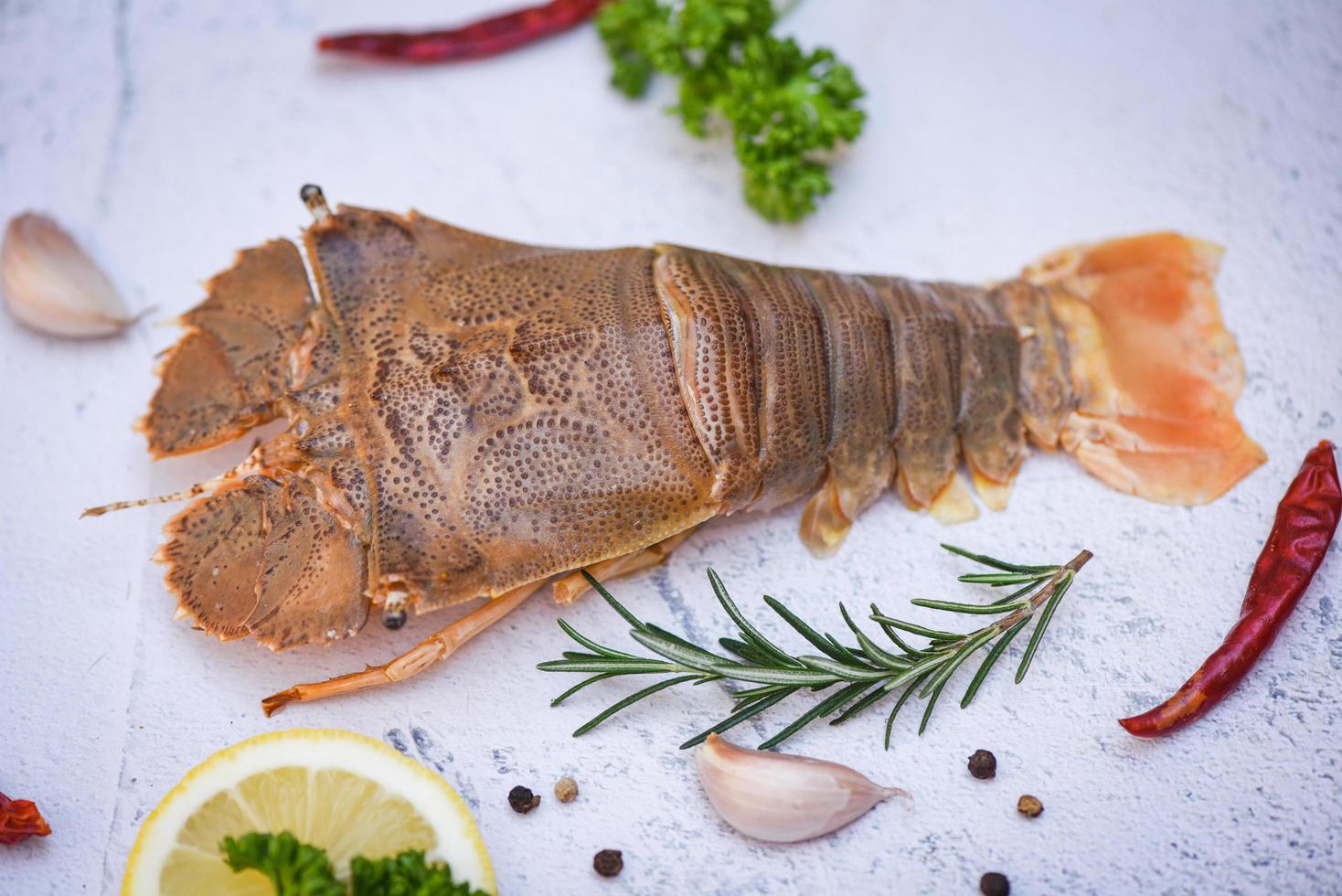 Raw flathead lobster shrimps with herbs and spices, fresh slipper lobster flathead for cooking in the seafood restaurant or seafood market photo