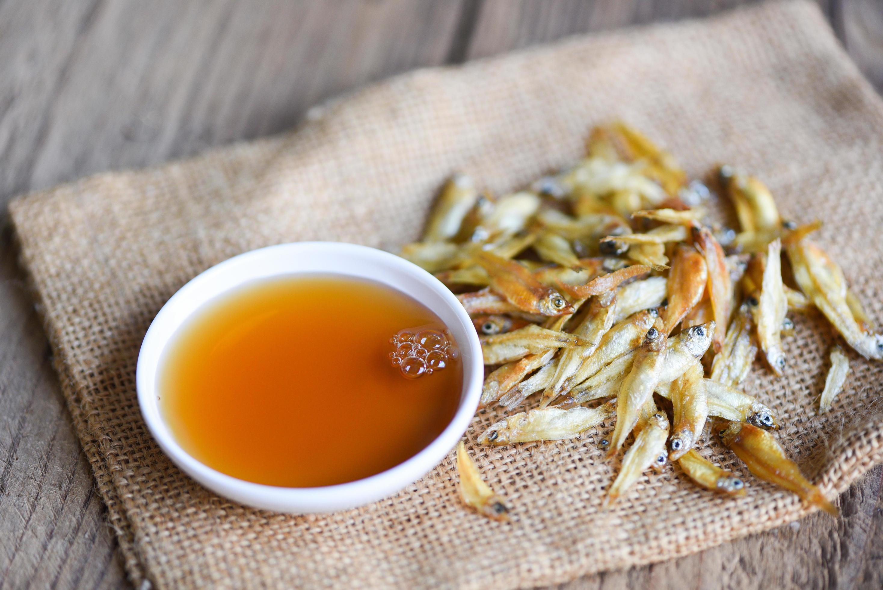 fish sauce on white bowl and small dried fish on sack, fish sauce