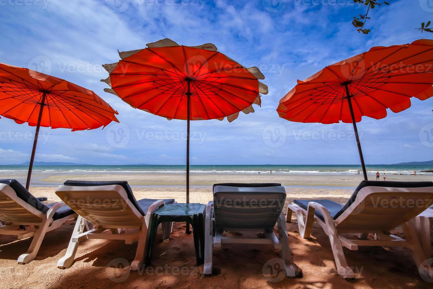 Una silla de playa con sombrilla y una silla de playa en la arena