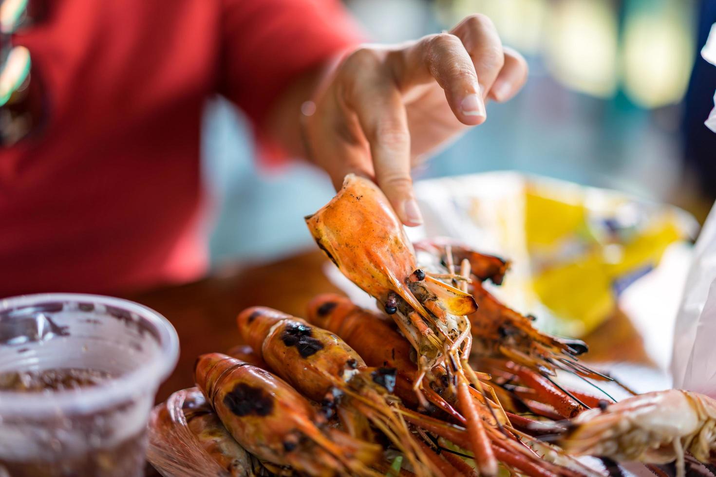 la mano de la mujer está pelando camarones a la parrilla. foto