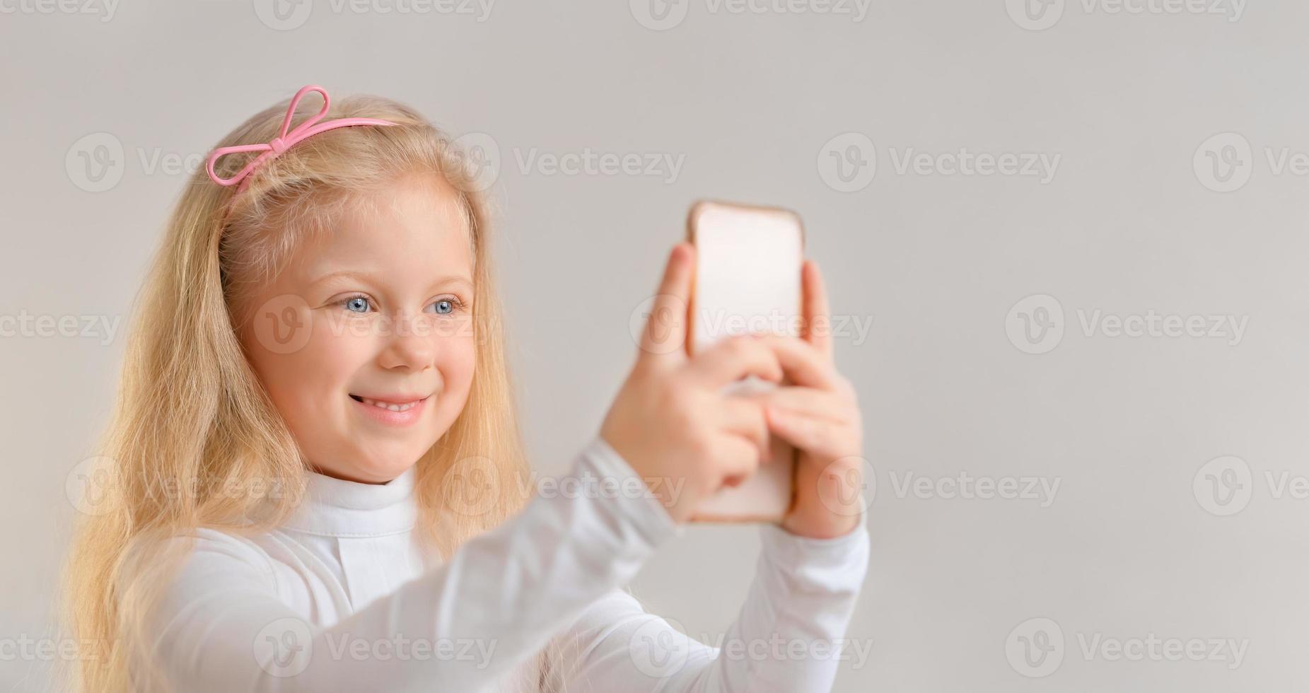 Beautiful smiling little girl taking a selfie photo with smartphone