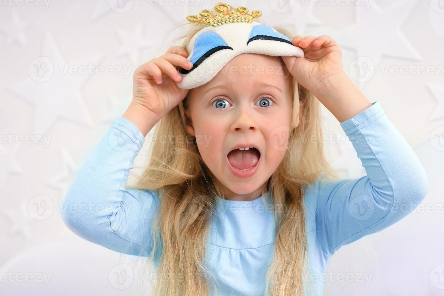 A little girl in a sleep mask overslept and screams in fright photo