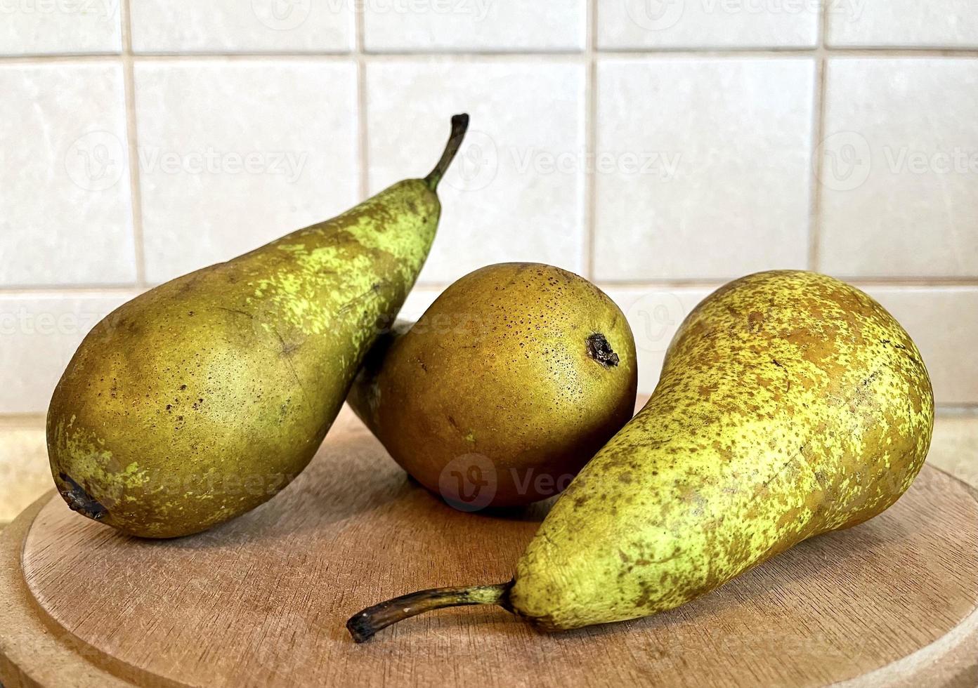 peras verdes sobre una superficie de madera en la cocina de cerca foto