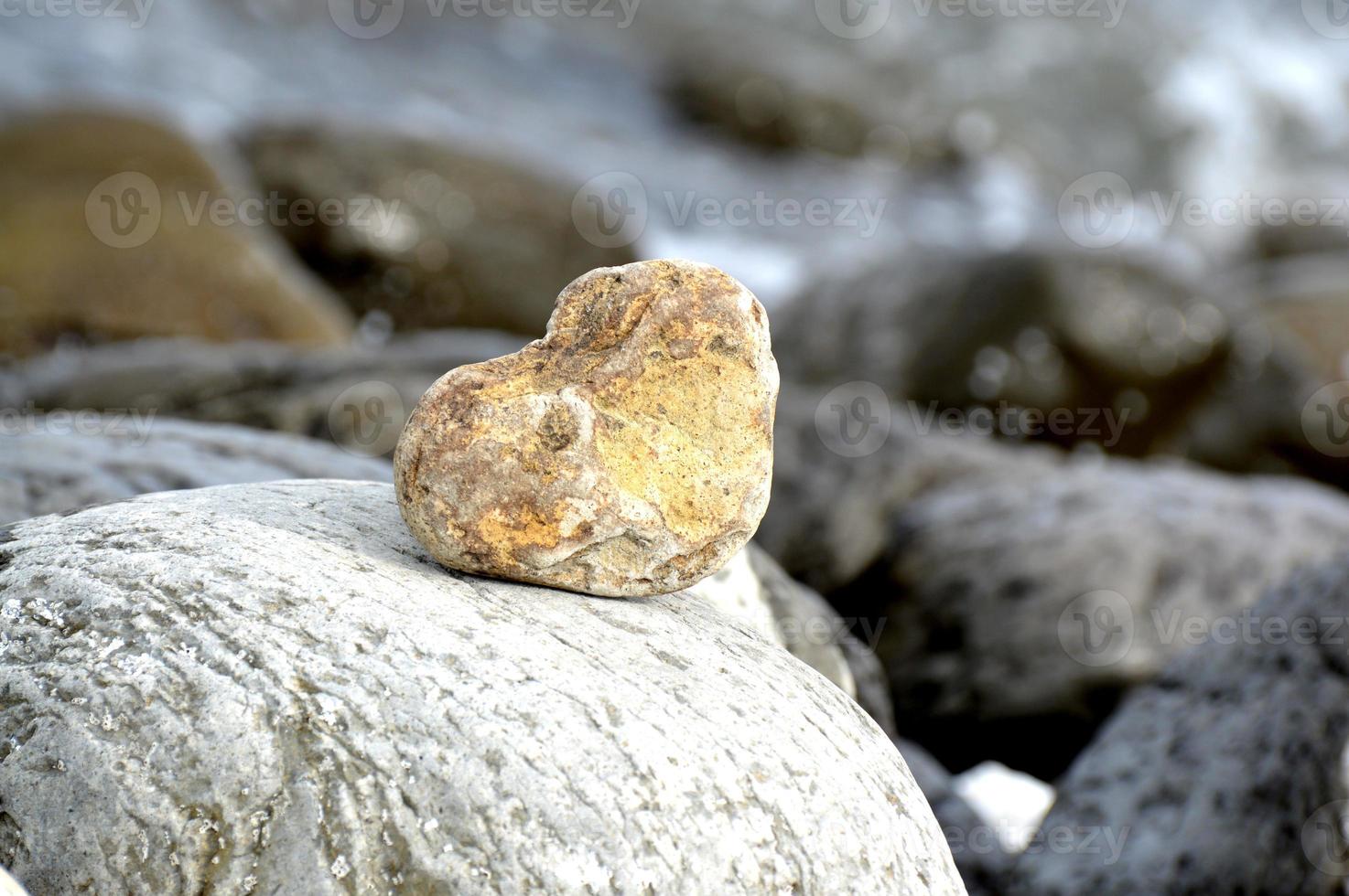 Heart shape stone against background of beach. Summer sunny day. Love, wedding and Valentine day concept. Finding beautiful and interesting stones. Beach vacation photo