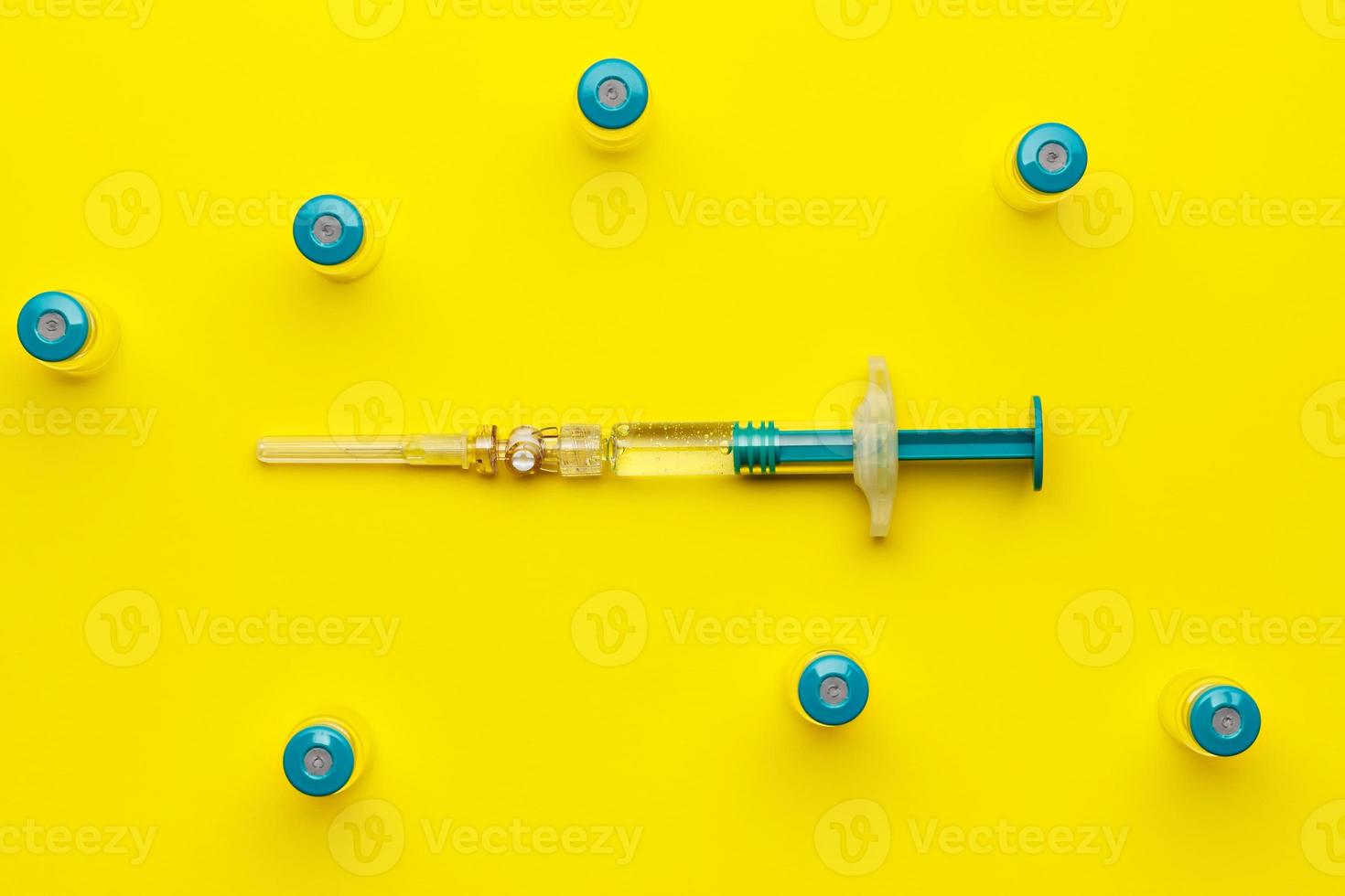 jeringa con varios viales médicos para inyectar sobre fondo amarillo. vista superior. foto