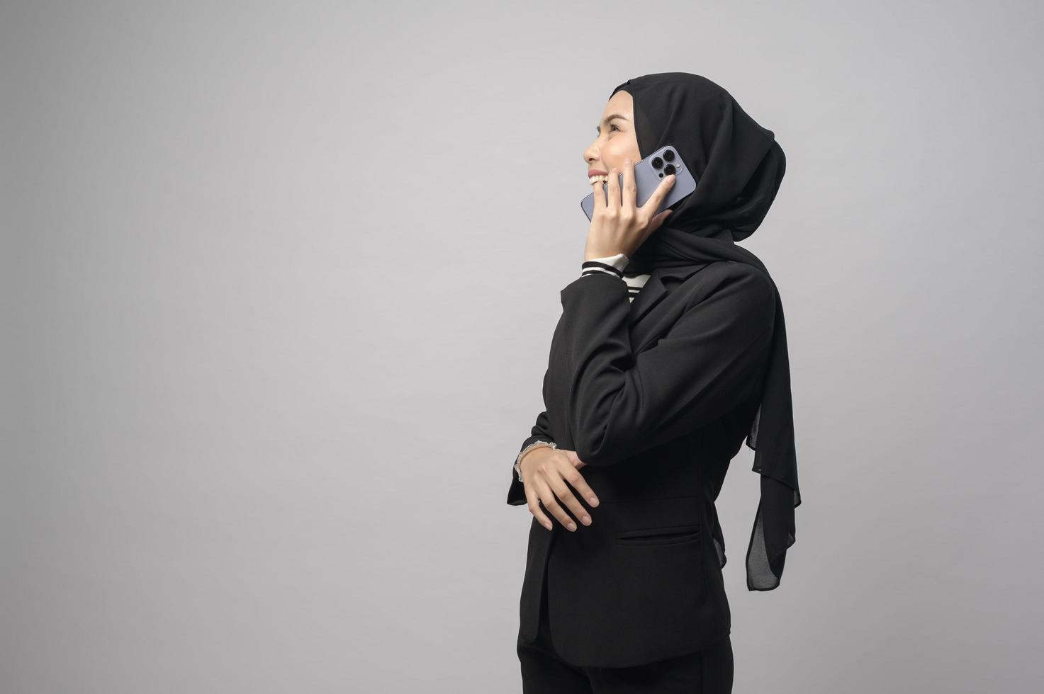 retrato de una mujer hermosa con hiyab usando un teléfono celular con fondo blanco foto