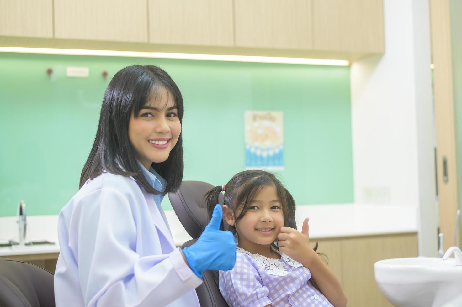 una niña linda con los dientes examinados por un dentista en una clínica dental, un chequeo dental y un concepto de dientes sanos foto