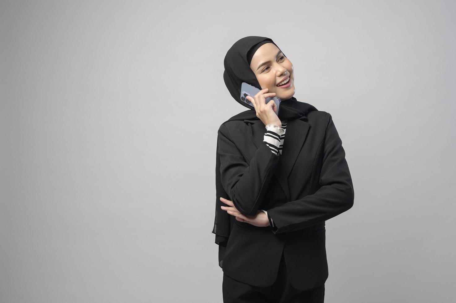 Portrait of beautiful woman with hijab using cellphone on white background photo