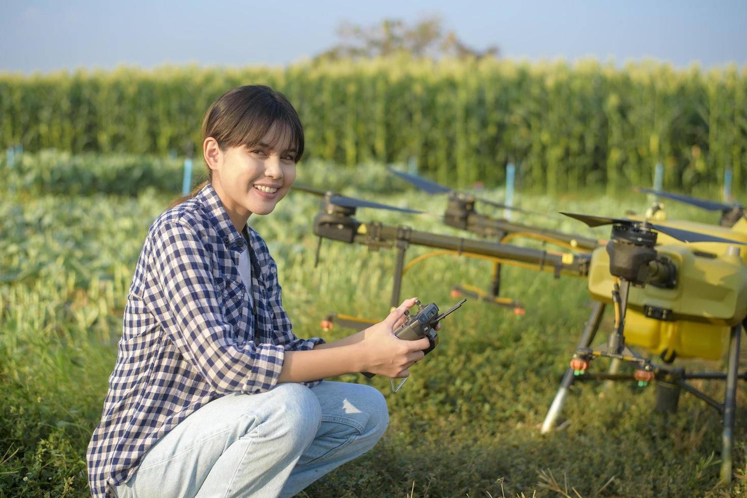 joven agricultor inteligente que controla la fumigación de fertilizantes y pesticidas con drones sobre tierras de cultivo, innovaciones de alta tecnología y agricultura inteligente foto