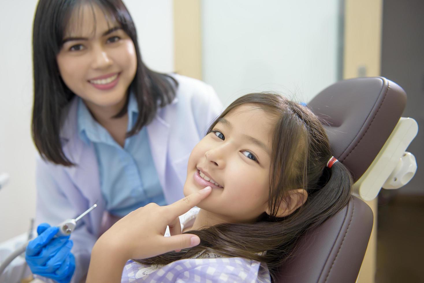 una niña linda con los dientes examinados por un dentista en una clínica dental, un chequeo dental y un concepto de dientes sanos foto