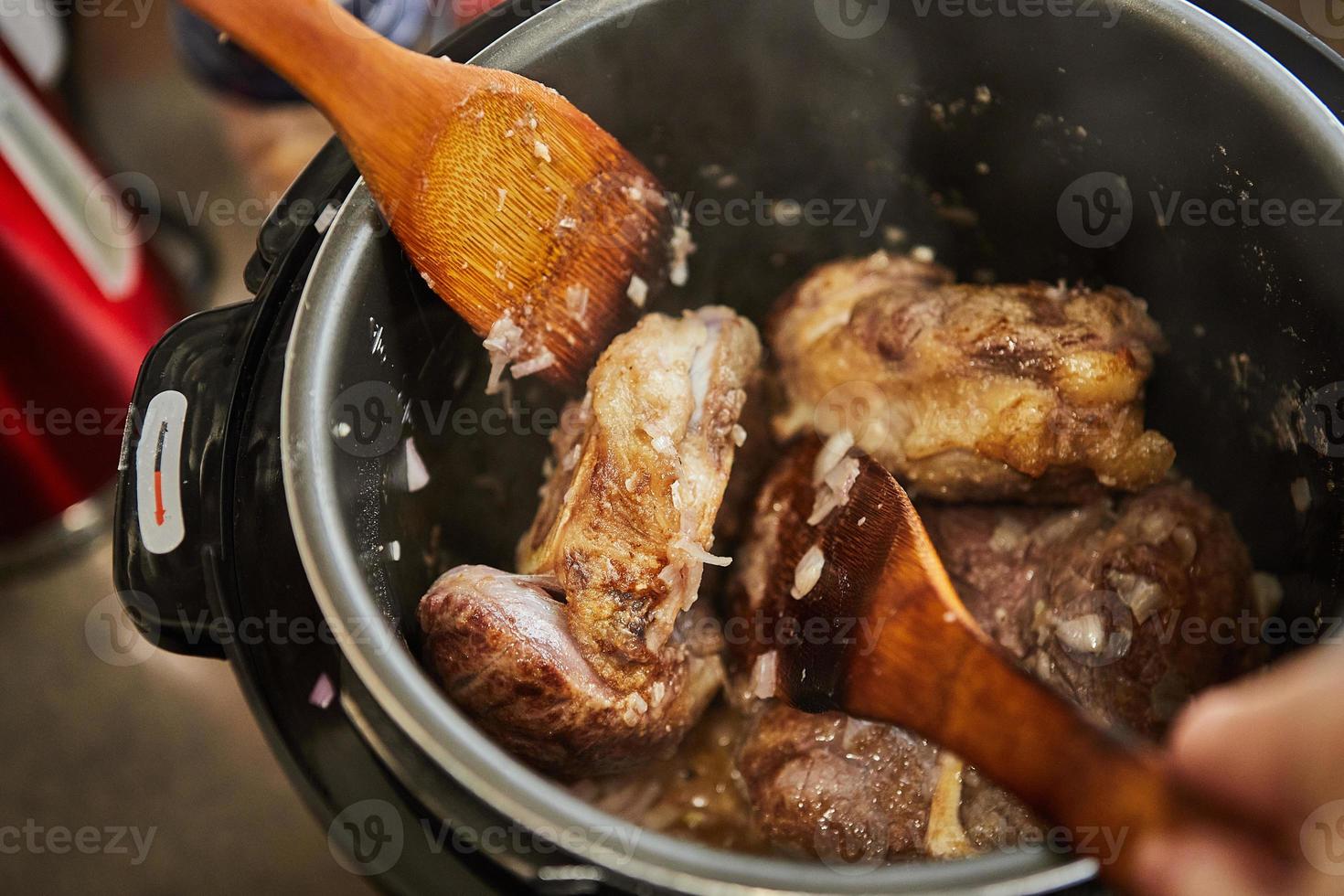 Ossobuco with spindle Beef is fried in pressure cooker and mixed with wooden spatulas. French gourmet cuisine photo