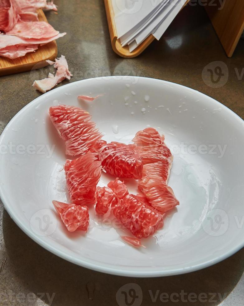 Red pomelo slices lie on plate ready for cooking photo