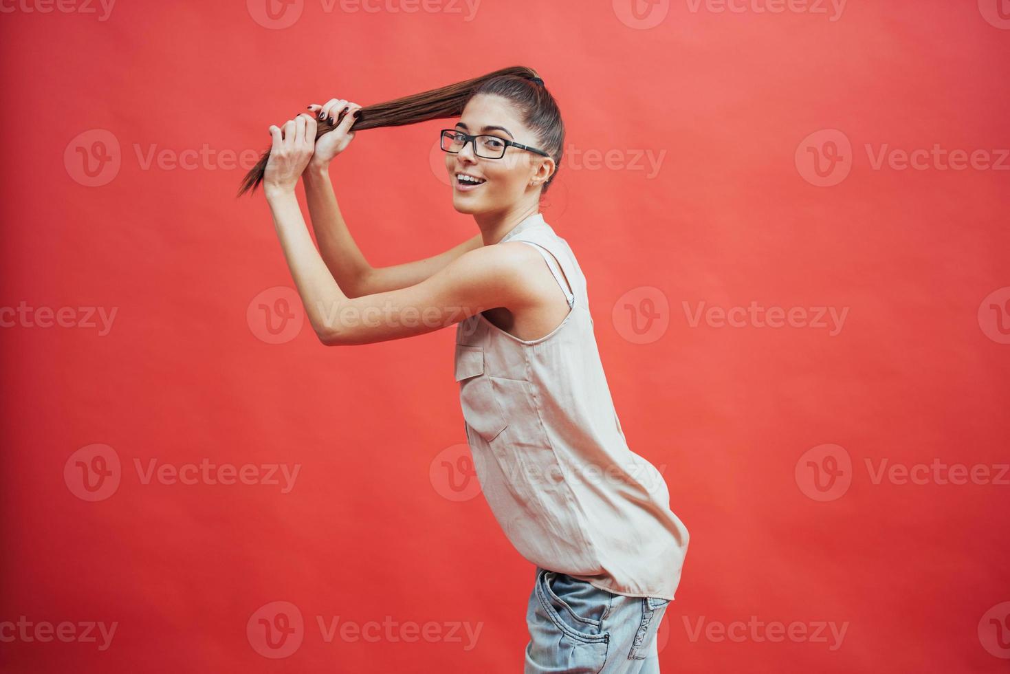 Beautiful young woman in glasses. On a beautiful red background. Beauty, fashion. Makeup. photo