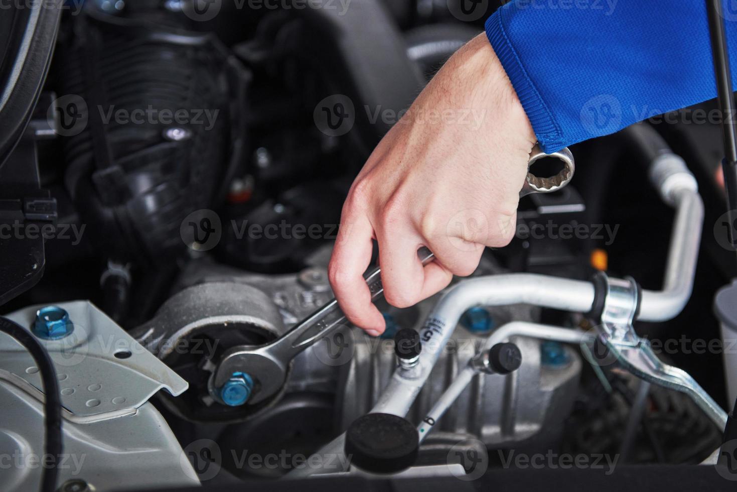 Hands of car mechanic with wrench in garage photo