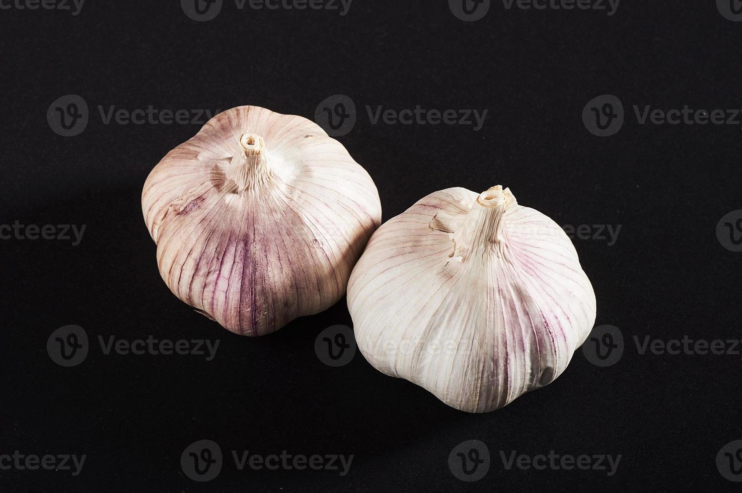 2 fresh garlic bulbs on a black background. photo